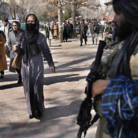 Afghan women pass next of Taliban fighter in Kabul, Afghanistan, Feb. 13, 2022. (AP Photo/Hussein Malla, File)