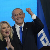 Likud leader Benjamin Netanyahu addresses supporters at the party's campaign headquarters in Jerusalem early on November 2, 2022, with his wife Sara at his side, as votes are counted in the general elections. (AP Photo/Tsafrir Abayov)
