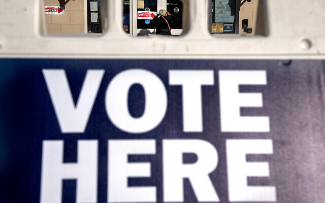 A woman is seen through a "vote here" sign, as she enters a polling site to vote in the midterm elections, in Washington, November 8, 2022. (Jacquelyn Martin/AP)