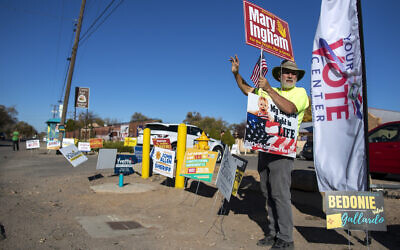 Stewart Ingham waves to motorists while campaigning for his wife Mary Ingham, a candidate for the New Mexico State House of Representatives, outside a polling center in the South Valley area of Albuquerque, N.M., Tuesday, Nov. 8, 2022 (AP/Andres Leighton)
