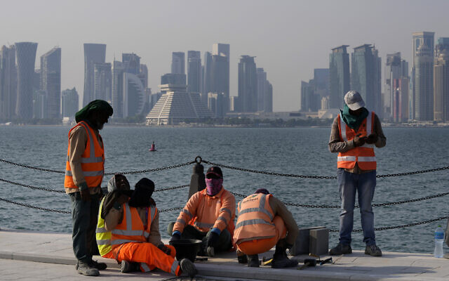 With the city skyline in the background, migrant workers work at the Doha port, in Doha, Qatar, Nov. 13, 2022. (AP Photo/Hassan Ammar)