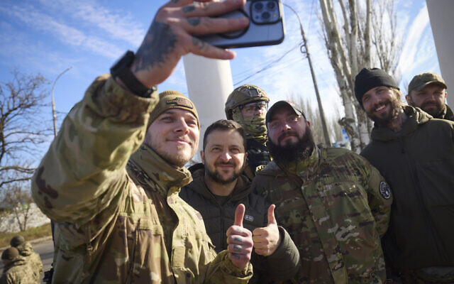 In this photo provided by the Ukrainian Presidential Press Office and posted on Facebook, Ukrainian soldiers take a selfie with President Volodymyr Zelensky, centre, during his visit to Kherson, Ukraine, Monday, Nov. 14, 2022. (Ukrainian Presidential Press Office via AP)