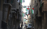 People walk under Palestinian flags in Yarmouk camp in Damascus Syria that has seen heavy fighting during the civil war, Nov. 2, 2022. (AP Photo/Omar Sanadiki, File)