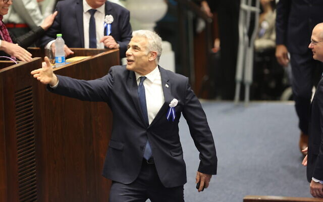 Outgoing Prime Minister Yair Lapid shakes hands during the swearing-in ceremony for the new Knesset, at the parliament building in Jerusalem, November 15, 2022. (Abir Sultan/Pool Photo via AP)