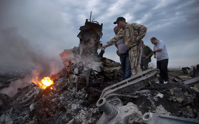 People inspect the crash site of a passenger plane near the village of Hrabove, Donetsk region of Ukraine, July 17, 2014. (AP Photo/Dmitry Lovetsky, File)