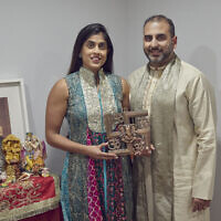 Sheetal Deo and her husband, Sanmeet Deo, hold a Hindu swastika symbol in their home in Syosset, New York, November 13, 2022. (Andres Kudacki/AP)