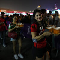 Fans carry their beers at a fan zone ahead of the FIFA World Cup, in Doha, Qatar, November 19, 2022. (AP Photo/Petr Josek)