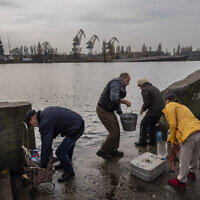 Residents of the recently liberated city of Kherson collect water from the Dnipro river bank, near the frontline, southern Ukraine, November 21, 2022. (Bernat Armangue/AP)