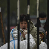 A woman has her routine COVID-19 test at a coronavirus testing site setup inside a residential compound in Beijing, Thursday, Nov. 24, 2022. (AP/Andy Wong)