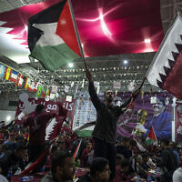 Palestinian soccer fans wave Qatari and Palestinian flags as they watch a live broadcast of the 2022 World Cup opening match between Qatar and Ecuador, at a covered gymnasium in Gaza City, on Nov. 20, 2022. (AP Photo/Fatima Shbair, File)
