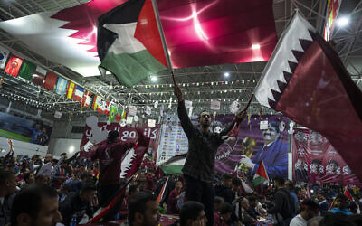 Palestinian soccer fans wave Qatari and Palestinian flags as they watch a live broadcast of the 2022 World Cup opening match between Qatar and Ecuador, at a covered gymnasium in Gaza City, on Nov. 20, 2022. (AP Photo/Fatima Shbair, File)
