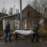 City workers collect the body of a man in Kherson, southern Ukraine, Friday, Nov. 25, 2022. The man died during a Russian attack on Thursday. (AP/Bernat Armangue)