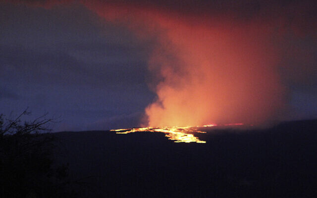 Lava pours out of the summit crater of Mauna Loa about 6:35 a.m. Monday, Nov. 28, 2022, as seen from Gilbert Kahele Recreation Area on Maunakea, Hawaii. Mauna Loa, the world’s largest active volcano,  began spewing ash and debris from its summit, prompting civil defense officials to warn residents on Monday to prepare in case the eruption causes lava to flow toward communities. (Chelsea Jensen/West Hawaii Today via AP)