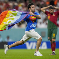 A pitch invader runs across the field with a rainbow flag during the World Cup group H soccer match between Portugal and Uruguay, at the Lusail Stadium in Lusail, Qatar, Nov. 28, 2022. (AP/Abbie Parr)