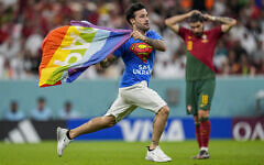 A pitch invader runs across the field with a rainbow flag during the World Cup group H soccer match between Portugal and Uruguay, at the Lusail Stadium in Lusail, Qatar, Monday, Nov. 28, 2022. (AP/Abbie Parr)