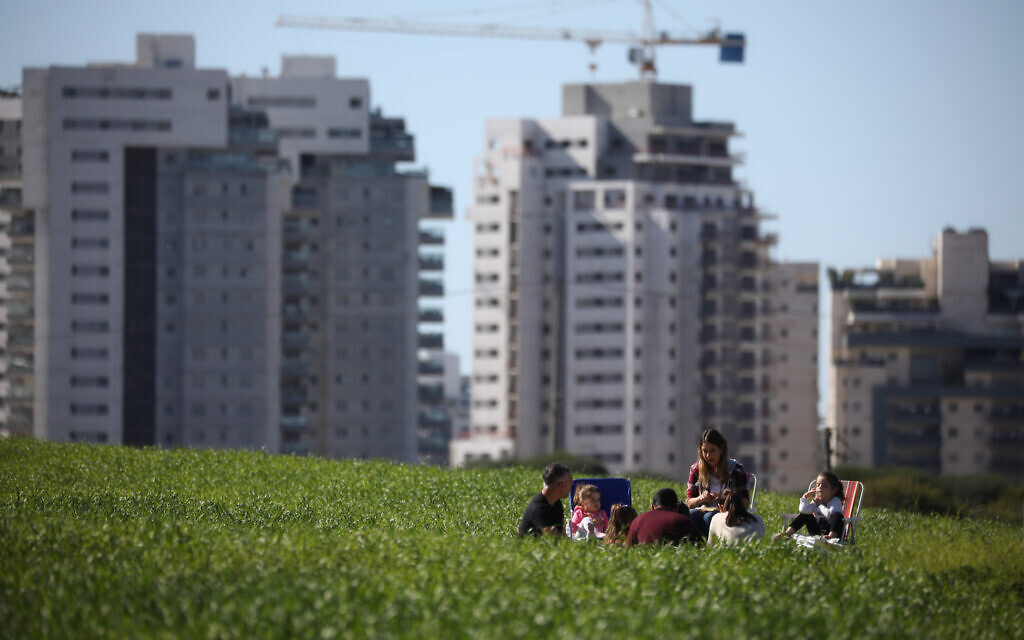 Israelis picnic in a field outside Rehovot, January 23, 2021. Buying a slice of agricultural land outside a city in hopes it gets rezoned is one way to get into the real estate game without a major investment, though it comes with substantial risks. (Doron Horowitz/Flash90)
