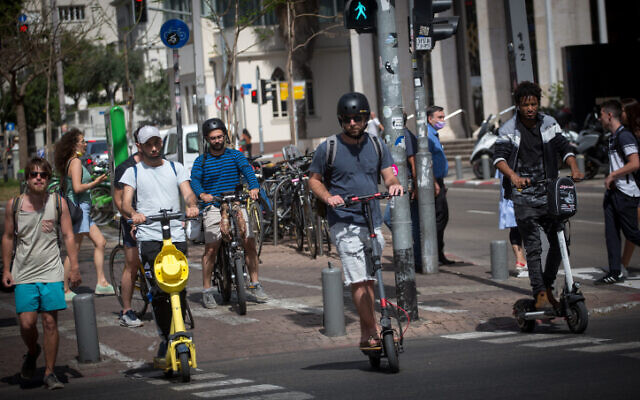 Israelis ride their electric scooters on Rothschild Boulevard in Tel Aviv, on May 5, 2021. (Miriam Alster/Flash 90)