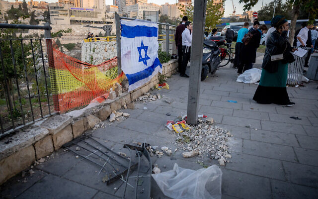 The Israeli flag hangs at the scene where a bomb exploded at the entrance to Jerusalem, on November 23, 2022. (Yonatan Sindel/Flash90)
