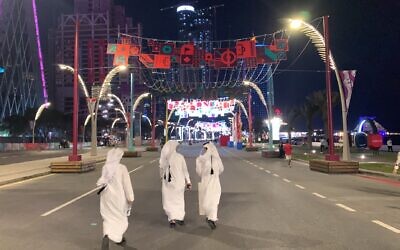 Qatari locals walk down Doha's Corniche Street following their country's opening-match loss to Ecuador, November 20, 2022. (Ash Obel/Times of Israel)