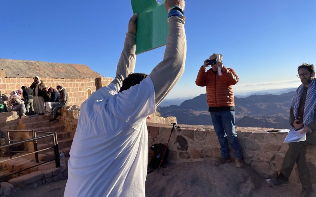 Yosef Abramowitz smashes tablets atop Jebel Musa in Egypt, thought by some to be the site of Mount Sinai, to symbolize the world’s lack of action on climate change, November 13, 2022. (Sue Surkes/Times of Israel)