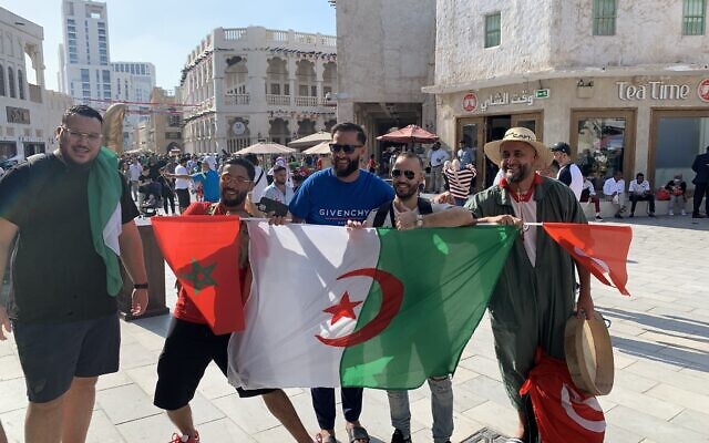 Fans from Morocco, Algeria and Tunisia hold their national flags in Doha's Souq Waqif, November 21, 2022. (Ash Obel/Times of Israel)