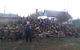An elderly Jewish man in the Dnipro region of Ukraine stands before a delivery of firewood made by JDC as part of an effort to support Ukrainian Jews in advance of a punishing winter. (Courtesy of the JDC via JTA)