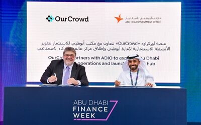OurCrowd founder and CEO Jon Medved, left, signs an agreement to expand the company in the UAE with support from the Abu Dhabi Investment Office, November 2022. Acting director-general of ADIO, Abdulla Abdul Aziz AlShamsi, also signed the agreement. (Courtesy / OurCrowd)