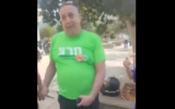 A Netanya resident wearing a Meretz shirt holds a set of tefillin, or phylacteries, against his crotch at a Chabad booth in Netanya, outside a school where a voting booth is located, on Israel's general elections day, November 1, 2022. (Twitter screenshot: used in accordance with Clause 27a of the Copyright Law)