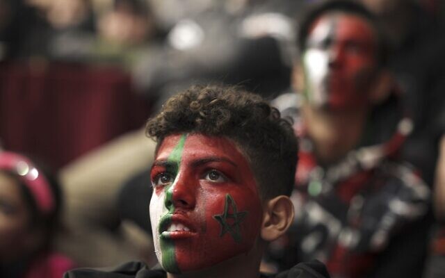 Palestinian football fans with faces painted in the colours of the national and Moroccan flags watch the Qatar 2022 World Cup round 16 soccer match between Portugal and Morocco in Gaza City, on December 10, 2022. (MOHAMMED ABED / AFP)