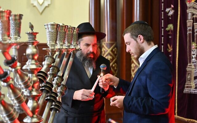 A rabbi and a member of the Jewish community light a candle for a menorah during a ceremony for the Jewish holiday of Hanukkah at the Kharkiv Choral Synagogue in Kharkiv, eastern Ukraine, on December 18, 2022, amid the Russian invasion of Ukraine. (Sergey BOBOK / AFP)