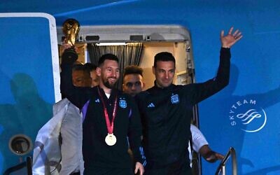 Argentina's national soccer team captain Lionel Messi (L) holds the FIFA World Cup Trophy alongside Argentina's coach Lionel Scaloni as they step off a plane upon arrival at Ezeiza International Airport after winning the Qatar 2022 World Cup tournament, in Ezeiza, Buenos Aires province, Argentina on December 20, 2022. (Luis ROBAYO / AFP)