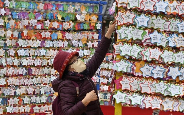 A Buddhist follower attaches name cards with wishes during celebrations for the New Year at Jogye temple in central Seoul on December 31, 2022. (Jung Yeon-je / AFP)