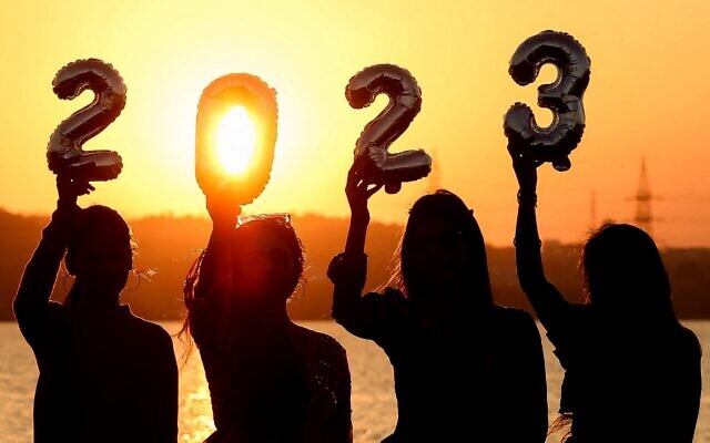 Women are silhouetted against the setting sun as they hold up numeric shaped balloons on the eve of New Year in Bhopal, India, on December 31, 2022. (Gagan Nayar/AFP)