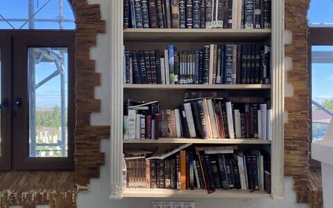 Books in both Hebrew and Russian sit on a bookshelf at Medzhybizh. (Jacob Judah/ JTA)