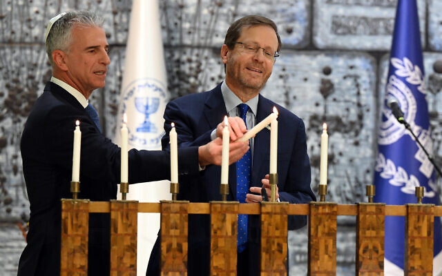President Isaac Herzog (right) and Mossad head David Barnea light the Hanukkiah at the President's House, December 22, 2022. (Haim Tzach/GPO)