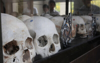 Visitors watch human skulls and bones of victims in Khmer Rouge regime on display at Choeung Ek memorial outside Phnom Penh, Cambodia, April 17, 2017. (AP Photo/Heng Sinith)