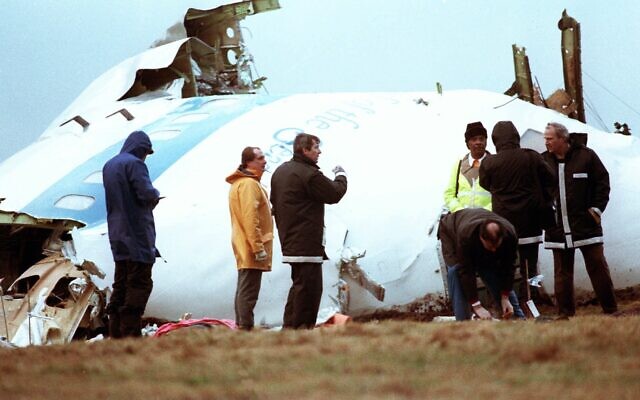 Unidentified crash investigators inspect the nose section of the crashed Pan Am flight 103, a Boeing 747 airliner in a field near Lockerbie, Scotland, December 23, 1988. (Dave Caulkin/AP)