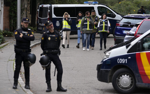 Police officers stand guard as other officers in yellow vests walk back at the cordoned off area next to the Ukrainian embassy in Madrid, Spain, Wednesday, Nov. 30, 2022. (AP Photo/Paul White)