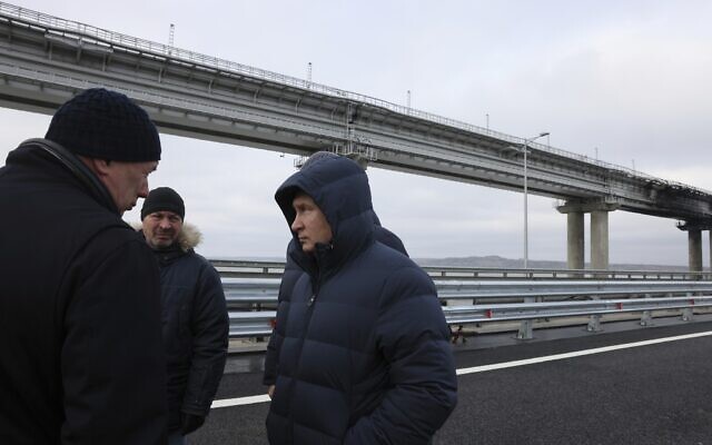 Russian President Vladimir Putin, center, listens to Deputy Prime Minister Marat Khusnullin, left, as he visits the Crimean Bridge connecting Russian mainland and Crimean peninsula over the Kerch Strait, which was damaged by a truck bomb attack in October, after restoration works, not far from Kerch, Crimea, Monday, Dec. 5, 2022. (Mikhail Metzel, Sputnik, Kremlin Pool Photo via AP)