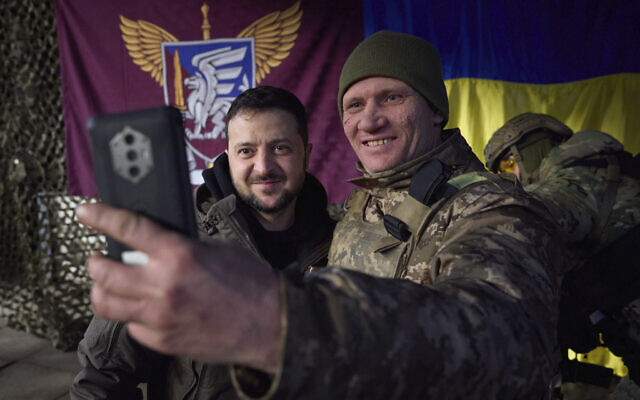 A Ukrainian soldier takes a selfie with President Volodymyr Zelensky, left, during his visit to Sloviansk, Donbas region, Ukraine, December 6, 2022. (Ukrainian Presidential Press Office via AP)