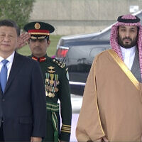 In this image taken from footage by Saudi State TV, Chinese President Xi Jinping, left, listens to the Chinese national anthem next to Saudi Crown Prince and Prime Minister Mohammed bin Salman in Riyadh, Saudi Arabia, Dec. 8, 2022. (Saudi Press Agency via AP)
