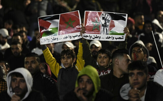 Palestinians wave banners with Moroccan and Palestinian flags as they watch a live broadcast of the World Cup quarterfinal soccer match between Morocco and Portugal played in Qatar, in the West Bank town of Nablus,  Dec. 10, 2022. Arabic on banner reads 'One people, one country'. (AP Photo/Majdi Mohammed)