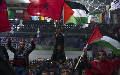 Palestinians wave Moroccan and Palestinian flags as they watch a live broadcast of the World Cup semifinal soccer match between Morocco and France played in Qatar, in Gaza City, Wednesday, Dec. 14, 2022. (AP/Fatima Shbair)