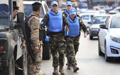 Irish UN peacekeepers pass a Lebanese soldier, left, as they arrive to investigate the scene where unidentified open gunfire came on a UN peacekeeper convoy in the al-Aqbiya village, south Lebanon, December 15, 2022. (AP Photo/Mohammed Zaatari)