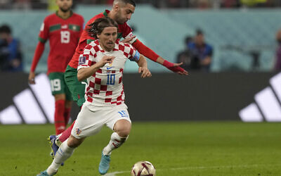 Croatia's Luka Modric, front, duels for the ball with Morocco's Hakim Ziyech during the World Cup third-place playoff soccer match between Croatia and Morocco at Khalifa International Stadium in Doha, Qatar, December 17, 2022. (AP Photo/Frank Augstein)