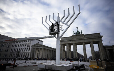 Rabbi Yehuda Teichtal, on the platform left, and Rabbi Segal Shmoel, on the platform right, inspect a giant Hanukkah Menorah, set up by the Jewish Chabad Educational Center ahead of the Jewish Hanukkah holiday, in front of the Brandenburg Gate at the Pariser Platz in central Berlin, Germany, Dec. 16, 2022. (AP Photo/Markus Schreiber)