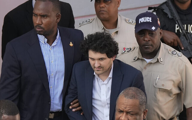 FTX founder Sam Bankman-Fried, center, is escorted out of Magistrate Court into a Corrections van, following a hearing in Nassau, Bahamas, December 19, 2022. (AP Photo/Rebecca Blackwell)