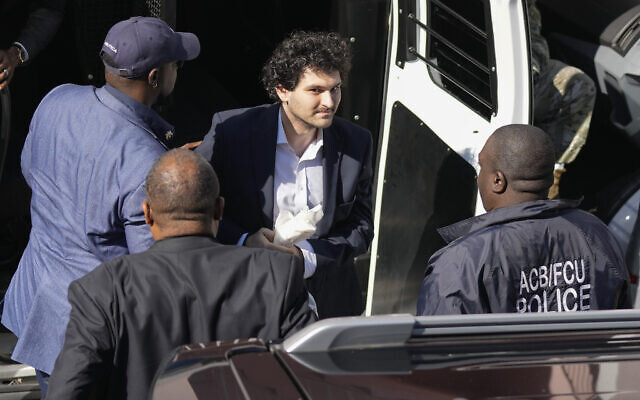 FTX founder Sam Bankman-Fried, center, is escorted from a Corrections Department van as he arrives at the Magistrate Court building for a hearing, in Nassau, Bahamas Dec. 21, 2022.(AP/Rebecca Blackwell)