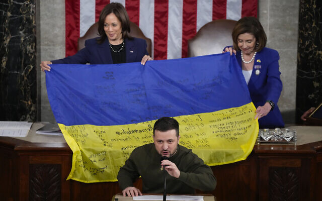 US Vice President Kamala Harris and House Speaker Nancy Pelosi, right, react as Ukrainian President Volodymyr Zelensky presents lawmakers with a Ukrainian flag autographed by front-line troops in Bakhmut, in Ukraine's contested Donetsk province, as he addresses a joint meeting of Congress on Capitol Hill in Washington, December 21, 2022. (AP Photo/Jacquelyn Martin)