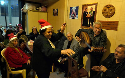 Amira Mansour (C) dances as Samir Damouni plays the Oud during a community Christmas dinner for elderly residents at the only majority-Christian Palestinian refugee camp, in Dbayeh, north of Beirut, Lebanon, December 21, 2022. (AP/Bilal Hussein)